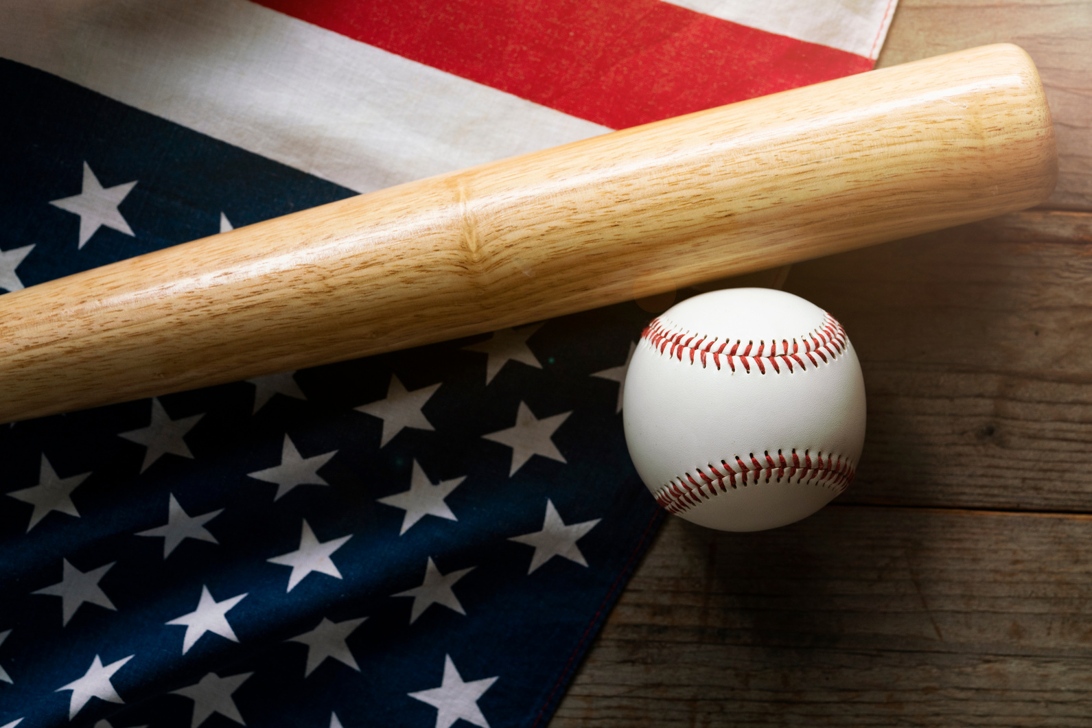 baseball and baseball bat with American flag in the background
